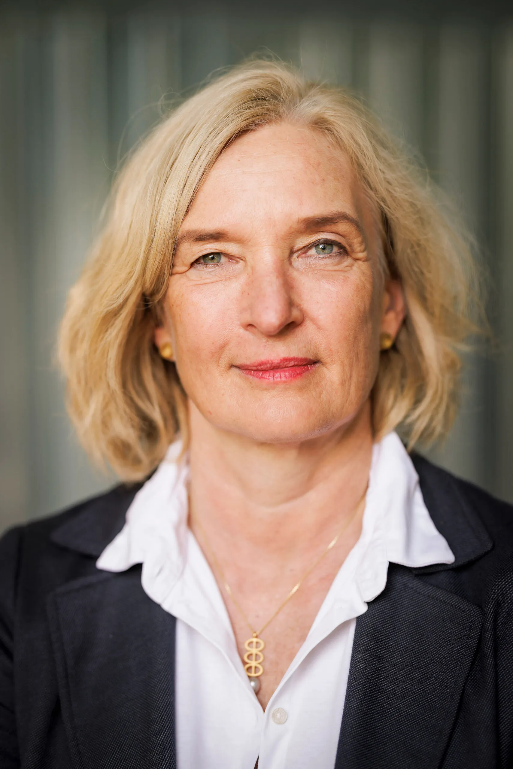 Business Portraits einer Frau mit blondem Haar. Sie trägt ein dunkles Jacket und eine weiße Bluse.